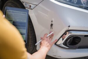 An insurance adjuster assessing car damage, emphasizing the aggressive tactics used in the repair process.