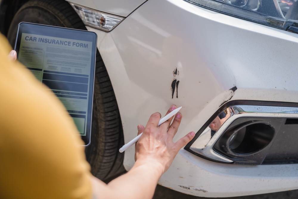 An insurance adjuster assessing car damage, emphasizing the aggressive tactics used in the repair process.