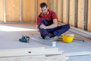 A man sitting on the floor with a hammer and tool, representing personal injury compensation in Texas.