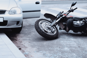A motorcycle lies on the ground beside a car, indicating a recent accident in Texas.