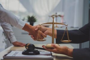 A handshake between two business professionals at a desk with a scale, representing Texas personal injury law discussions.