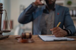 An experienced personal injury lawyer writing on a legal document in his office, focused and professional.