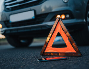 A car with a malfunctioning alarm and a damaged orange warning triangle, indicating a post-accident situation in Houston.